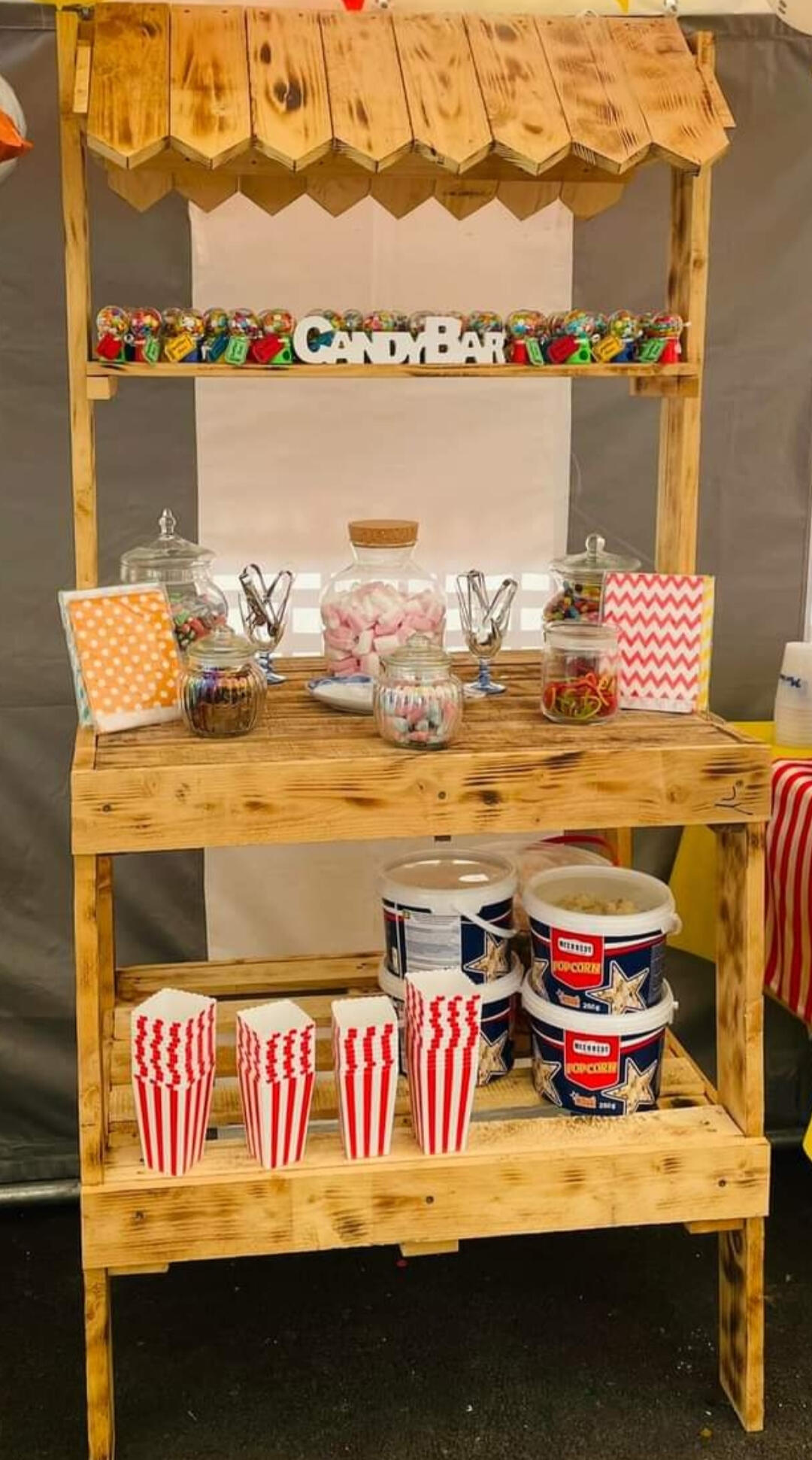 Candy bar Piko Event | Photo d'un candy bar en bois fait main avec bois recyclé, garnis de bonbonnières pleines et de seaux à pop corn