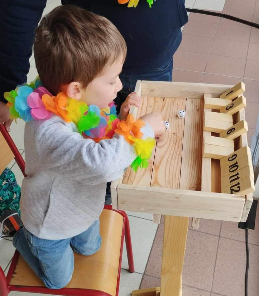 Piko Event | Photo du jeu shut the box, un enfant y joue guidé par un adulte. Jeu en bois loué pour anniversaire. Lien vers les règles du jeu